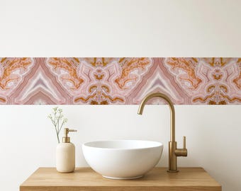 May include: A bathroom scene featuring a white vessel sink, a gold faucet, and a matching soap dispenser on a wooden vanity. Above, a decorative band with a pink, white, and gold agate pattern adds a touch of elegance.