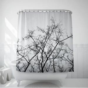 May include: Black and white shower curtain featuring a silhouette of bare tree branches against a white background.