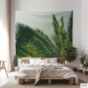 a bedroom with a large tapestry of palm leaves hanging on the wall behind a bed.