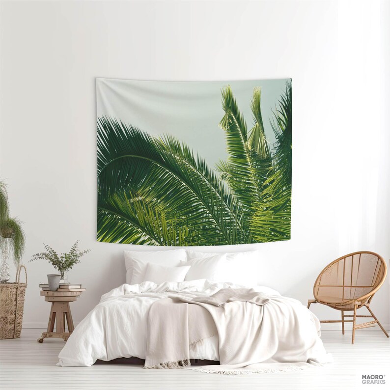 a bedroom with a large tapestry of palm leaves hanging on the wall above a bed. The tapestry is predominantly green and white, creating a tropical ambiance in the room.