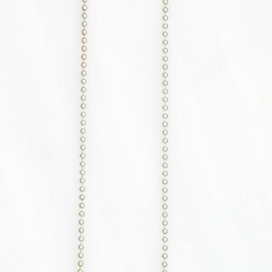 May include: A silver-toned necklace with a heart-shaped pendant. The pendant has Hebrew text and a black leather accent. The necklace chain is made of small, round beads and has a magnetic clasp.