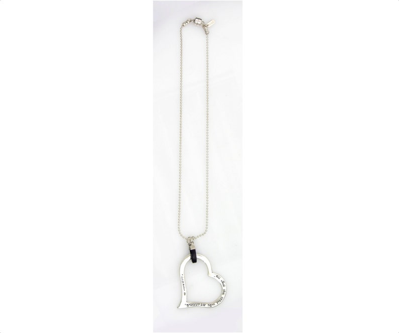 May include: Silver-toned necklace featuring a large, open heart pendant. The heart has an inscription and hangs from a delicate chain. The necklace is displayed against a white background, highlighting its design and details.