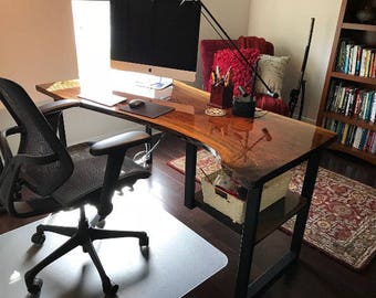 May include: A black office chair with a mesh back and a wood desk with a live edge top and black metal legs. The desk has a clear epoxy finish and a shelf underneath. There is a computer monitor, a mouse, and a keyboard on the desk.