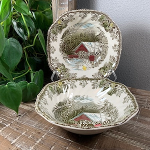 May include: Two vintage ceramic bowls with a green and brown floral pattern. The bowls feature a scene of a red covered bridge in a winter landscape.