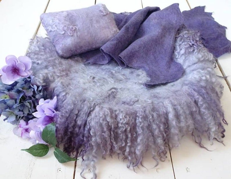 May include: A purple and white fluffy newborn photography backdrop with a matching pillow and blanket. The backdrop is made of a soft, fuzzy material and is perfect for creating beautiful photos of newborns.