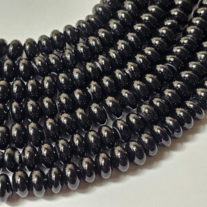 May include: A strand of black onyx beads, each bead is oval shaped and has a glossy finish.