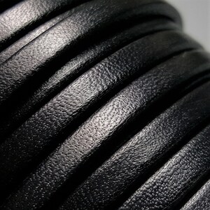 May include: Close-up of black leather cord, showing the textured surface and the way it coils.