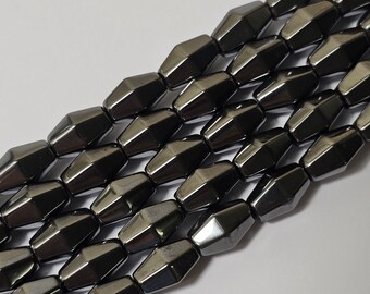 Peut inclure: Un brin de perles de pierres précieuses facettées noires. Les perles sont en forme d'hexagones allongés et ont une finition brillante et métallique.