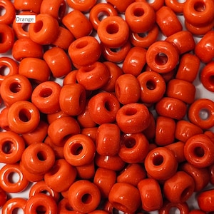 Puede incluir: Un montón de cuentas de plástico de color naranja. Las cuentas son redondas y tienen un agujero en el centro. Son perfectas para manualidades y la elaboración de joyas.