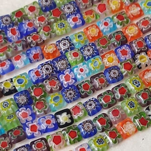 May include: A strand of colorful square glass beads with intricate floral patterns. The beads are made of Murano glass and have a variety of colors, including blue, green, red, yellow, and white.