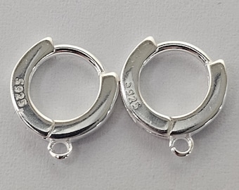 May include: Two silver-colored hoop earrings. Each earring has a hinged closure and a small loop at the bottom. The text "S925" is stamped on each earring. The earrings are designed for pierced ears.