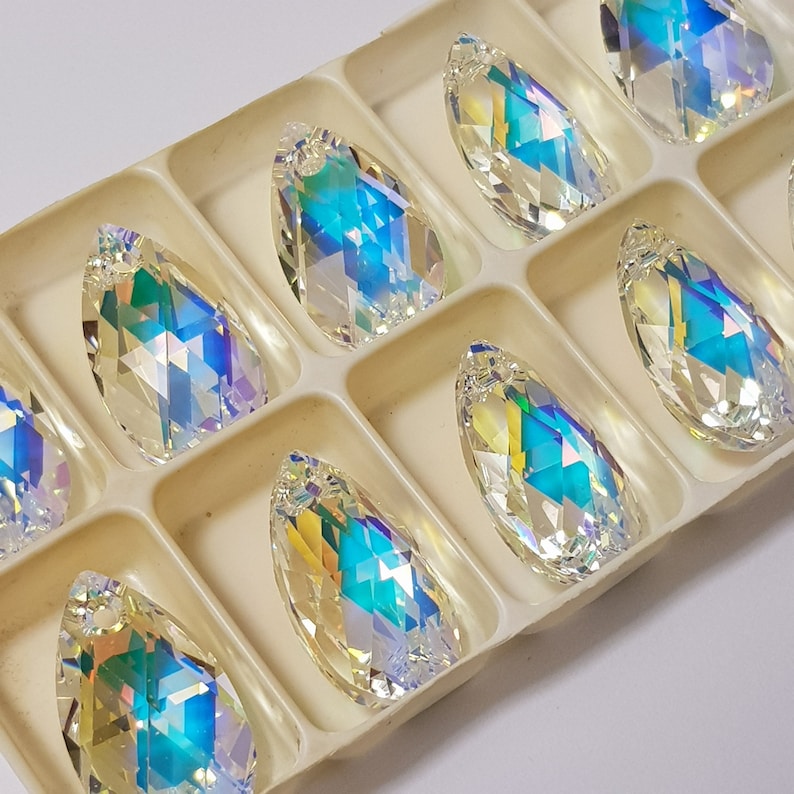 May include: A set of ten iridescent teardrop-shaped crystal pendants in a white plastic storage box. The crystals are clear with a rainbow effect.