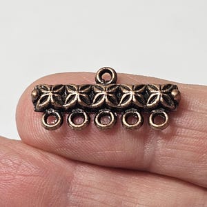 May include: A copper-toned metal connector with a decorative floral design and six loops for attaching jewellery or other crafts.