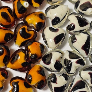 May include: Assortment of heart-shaped glass beads with black and white swirl patterns and brown and black swirl patterns.