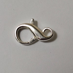May include: Silver-toned lobster clasp with a smooth finish. The clasp is shaped like an infinity symbol.