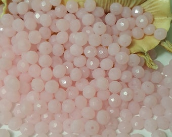 May include: A large pile of pale pink faceted glass beads. The beads are round and have a smooth, polished finish.