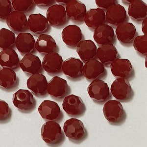 May include: A pile of red faceted glass beads. The beads are small and round, with a shiny finish.