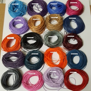 May include: Assortment of 20 spools of waxed cotton cord in various colours, including blue, purple, orange, red, and grey. Each spool is labelled with the colour and size of the cord.