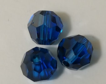 May include: Three faceted blue glass beads. The beads are round and have a shiny finish.