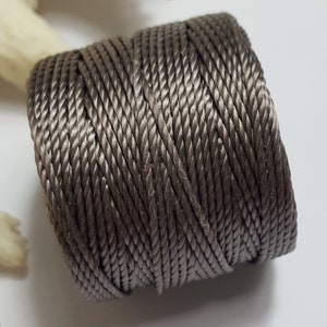 以下が含まれることがあります： グレーのコードの糸巻き。クラフトやジュエリー作りに使用される糸です。