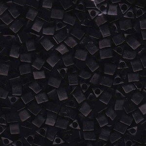 May include: A close-up shot of numerous small, black, square beads. Each bead features a hole, forming a geometric design. The beads are densely packed, filling the entire image frame.