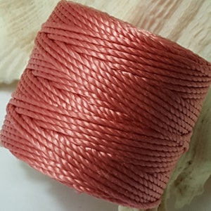 May include: A spool of coral pink twisted cord.