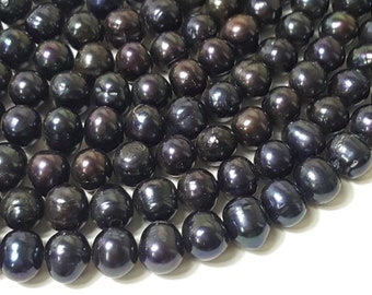 May include: A strand of black pearls, each pearl is round and smooth with a slight iridescent sheen.