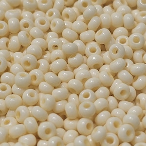 May include: A close-up view of a large quantity of small, round, white beads. The beads are smooth and glossy, and they are all the same size.