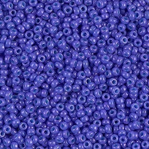 May include: A close-up view of a large quantity of small, round, blue glass beads. The beads have a slightly iridescent finish.