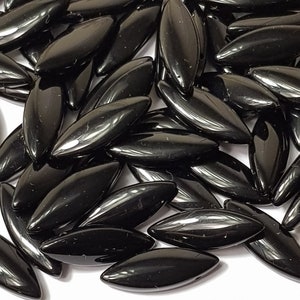 Puede incluir: Un montón de cuentas de vidrio negro en forma de lágrima. Las cuentas son brillantes y tienen una superficie lisa.