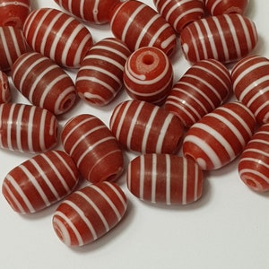 May include: A collection of red and white striped oval beads. The beads are made of glass and have a glossy finish.