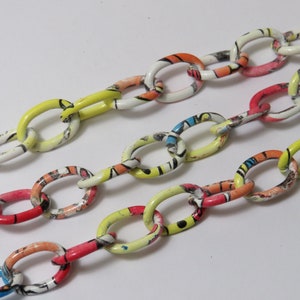 May include: Three colorful chains made of linked oval rings. Each ring is covered in a white base with a colorful pattern of red, yellow, blue, and orange.