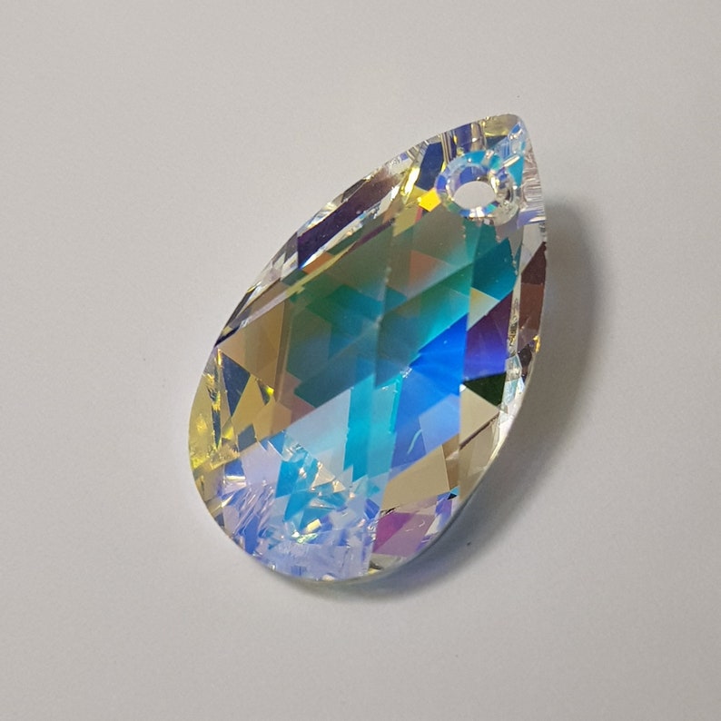 May include: A teardrop-shaped crystal pendant with a rainbow iridescent finish. The pendant has a small hole at the top for stringing.