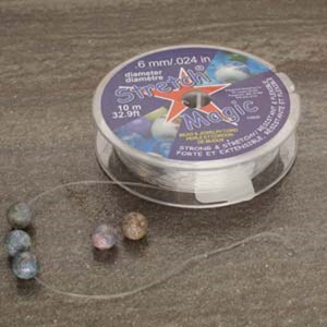 May include: A spool of clear elastic stretch magic beading thread with a purple label that reads "Stretch Magic" and "6 mm/.024 in diameter/diam&egrave;tre 10 m 32.9ft". The label also has a red star and the text "Bead & Jewelry by Cord Multi-Strand Elastic Strong & Stretchable Forte et Extensible".