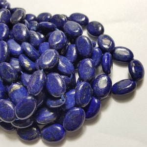 May include: A strand of oval-shaped lapis lazuli beads with gold flecks. The beads are a deep blue colour and have a smooth, polished finish.