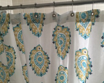 May include: White shower curtain with a blue and yellow paisley pattern.