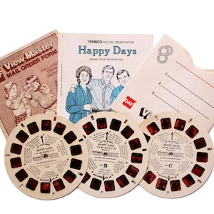 Könnte beinhalten: Vintage View-Master-Set mit "Happy Days". Enthält View-Master-Rollen, ein Bestellformular und ein Heft mit dem Titel und den Charakteren der Show. Die Rollen sind mit A, B und C beschriftet, und das Heft zeigt den Titel und die Charaktere.