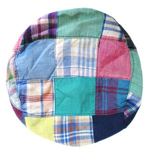 May include: A colorful patchwork hat featuring a variety of plaid and solid fabric squares in shades of blue, green, pink, and yellow. The hat has a rounded shape and a soft, casual appearance.