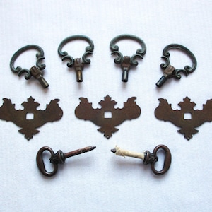 May include: Antique bronze-toned cabinet hardware set. Includes six keyhole escutcheons and three key-shaped pulls. The escutcheons have a decorative, ornate design. The pulls have a loop handle and a key-like stem. Ideal for vintage furniture restoration.