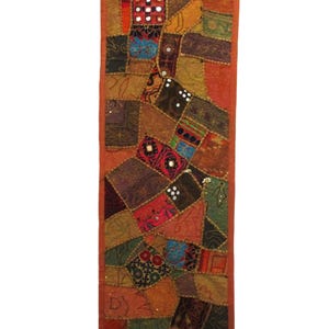 May include: A rectangular patchwork wall hanging with a variety of colors including orange, red, green, and brown. The design features a mix of geometric and patterned fabric pieces, some with reflective accents.