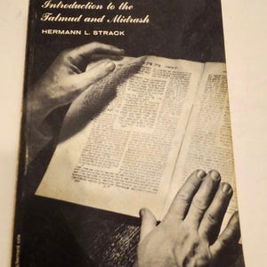May include: A vintage book titled "Introduction to the Talmud and Midrash" by Hermann L. Strack. The book's cover is black and white, with the title in elegant script. The open pages show text, and hands are visible holding the book.