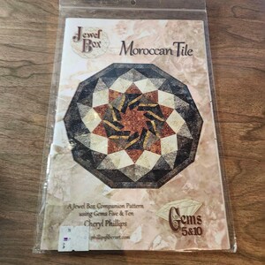 May include: A Jewel Box Moroccan Tile pattern in a clear plastic sleeve. The design features a geometric pattern in shades of brown, black, and cream. The text includes "Jewel Box", "Moroccan Tile", "Gems 5&10", and the name "Cheryl Phillips".