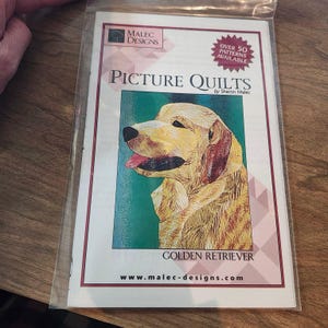 May include: A package containing a pattern book titled "Picture Quilts" by Sharon Malec. The cover features a golden retriever illustration with the text "Golden Retriever" and "Over 50 Patterns Available". The website www.malec-designs.com is also visible.