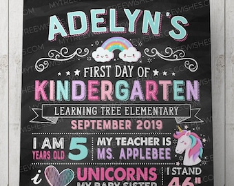 May include: Black chalkboard-style sign for a child's first day of kindergarten, with colourful text and graphics. Includes a rainbow, unicorn, and the child's name. It lists the child's age, teacher, and favourite things. The child is 117 cm tall.
