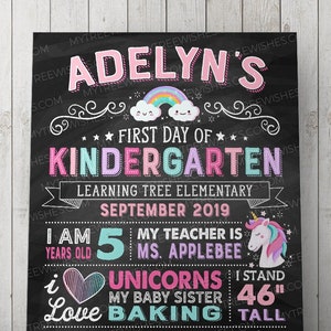 May include: A chalkboard-style sign with the text "Adelyn's First Day of Kindergarten." It includes a rainbow, unicorn, and details like age, teacher's name, and favorite things. The sign is 46 inches tall.