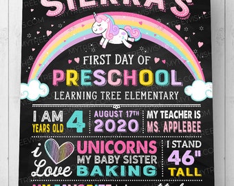 May include: Black chalkboard-style sign with the text "Sierra's First Day of Preschool." Features a rainbow, unicorn, and various facts about the child, including height of 46 inches. The sign is decorated with hearts and stars.