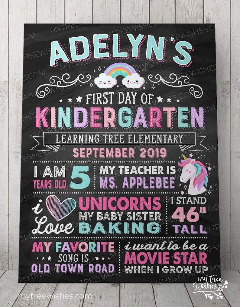 May include: Chalkboard-style sign for a child's first day of kindergarten. The sign is black with colorful text and graphics, including a rainbow, unicorn, and the child's name. It lists the child's age, teacher, and favorite things. The child is 46 inches tall.