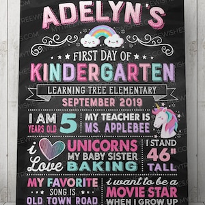 May include: A black chalkboard sign with a pink, blue, and purple rainbow and clouds. The text on the sign reads "Adelyn's First Day of Kindergarten Learning Tree Elementary September 2019 I am 5 years old My teacher is Ms. Applebee I love unicorns My baby sister 46" tall My favorite song is Old Town Road I want to be a movie star when I grow up".