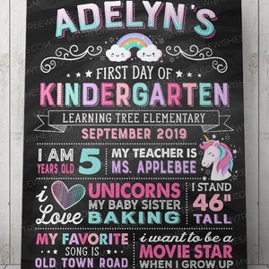 May include: A chalkboard-style sign with the text "Adelyn's First Day of Kindergarten." It includes a rainbow, stars, and a unicorn graphic. The sign states "I am 5 years old" and "I stand 46" tall."