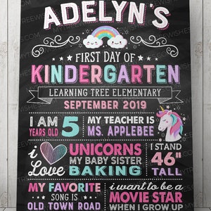 May include: A chalkboard-style sign for a child's first day of kindergarten. The sign features the name "Adelyn's" in pink and white, along with a rainbow, stars, and a unicorn. It includes the text "I stand 46 inches tall."
